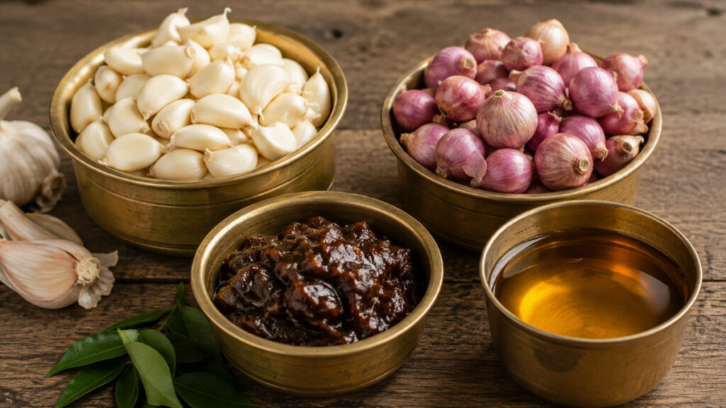 Peeled garlic cloves, shallots, tamarind, and sesame oil in brass bowls.