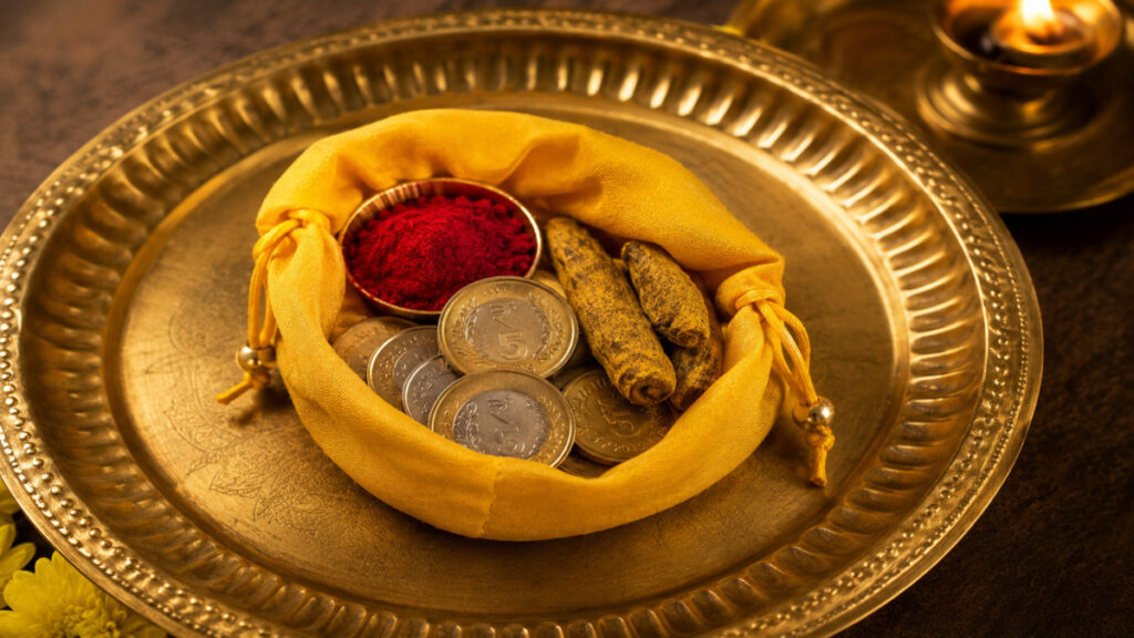 Yellow cloth pouch with raw turmeric and coins for financial growth and positivity.